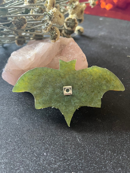 Bat car air freshener on a table with some flowers and crystals